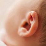 Gentle close-up of a newborn baby's ear, showcasing delicate features in a soft focus image.