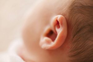 Gentle close-up of a newborn baby's ear, showcasing delicate features in a soft focus image.