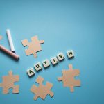 Puzzle pieces with 'autism' text on blue background, promoting autism awareness.